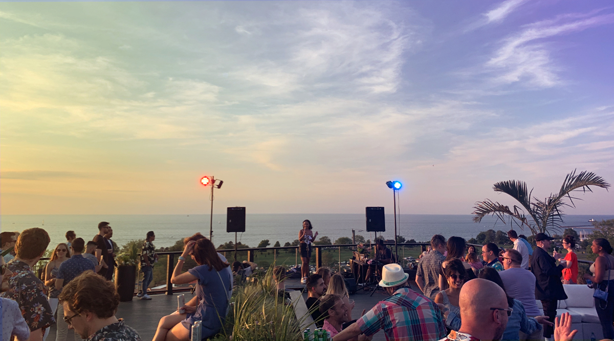Golden Hour crowd on a lakefront rooftop as the sun sets