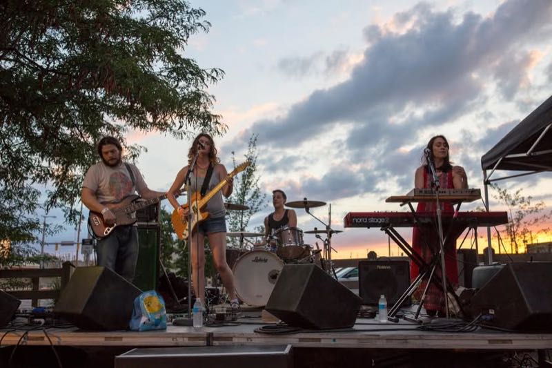 A band plays at sunset with keyboard and guitars.