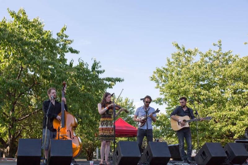 A string band with fiddle, upright bass and guitars plays in the evening light.